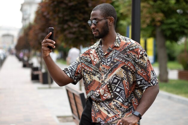 屋外で現代のスマートフォンで自分撮りをしているハンサムな男