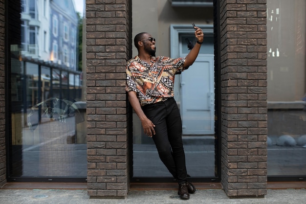 Handsome man taking selfie with modern smartphone outdoors