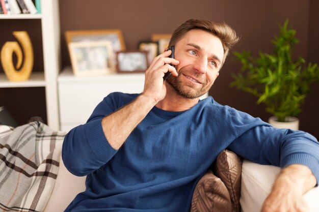 Handsome man talking on mobile phone at home