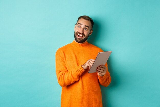 Handsome man thinking and using digital tablet, shopping online and pondering ideas