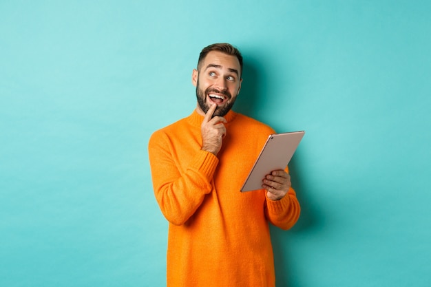 Handsome man thinking and using digital tablet, shopping online and pondering ideas