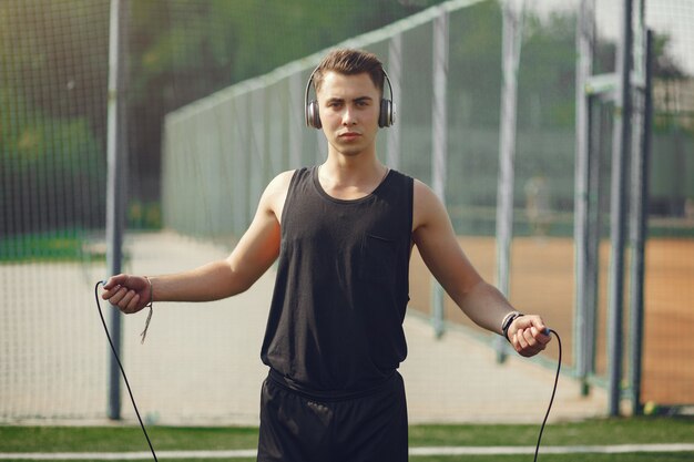 Handsome man training in a summer park with a jump rope