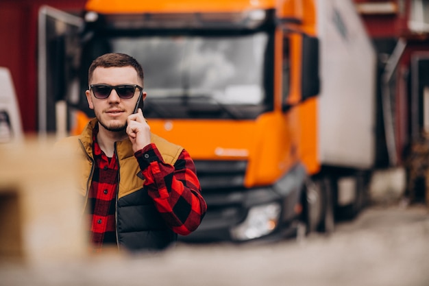 Бесплатное фото Красивый мужчина водитель грузовика, стоя у грузовика