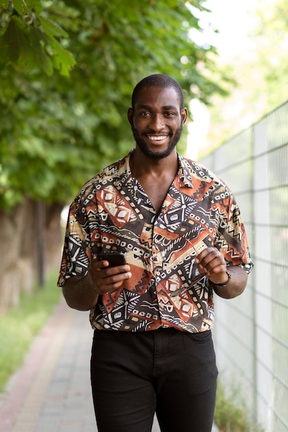 Foto gratuita bell'uomo che utilizza uno smartphone moderno all'aperto