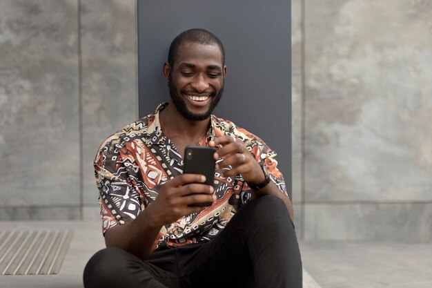 Handsome man using modern smartphone outdoors