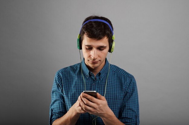Handsome man using phone to listen to music in headphones