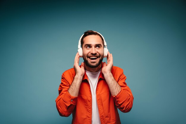 Handsome man in white headphones enjoys music on isolated background