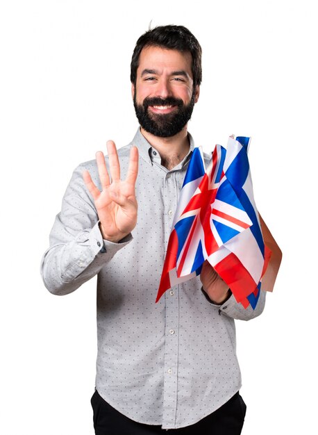 Handsome man with beard holding many flags and counting four