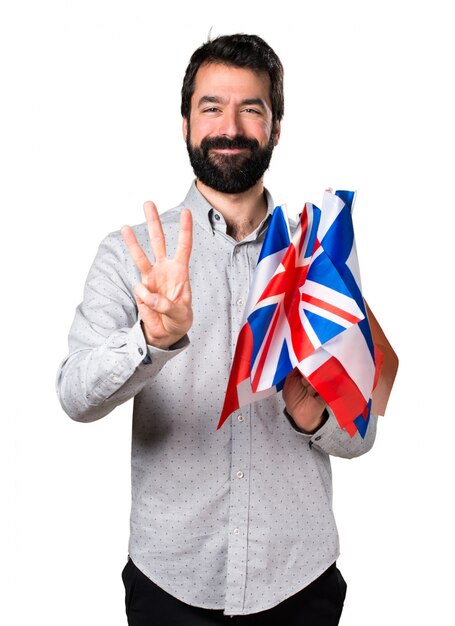 Handsome man with beard holding many flags and counting three