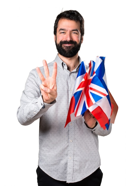 Handsome man with beard holding many flags and counting three