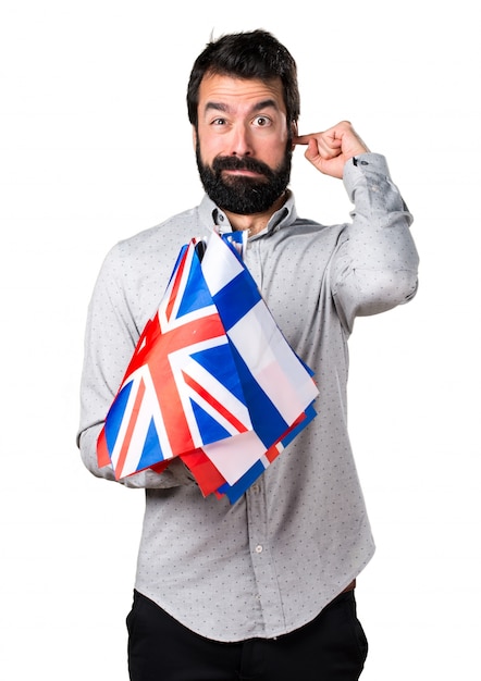 Handsome man with beard holding many flags and covering his ears