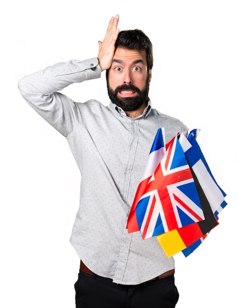 Handsome man with beard holding many flags and having doubts