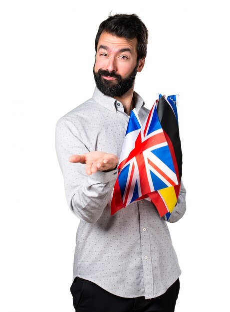 Handsome man with beard holding many flags and holding something