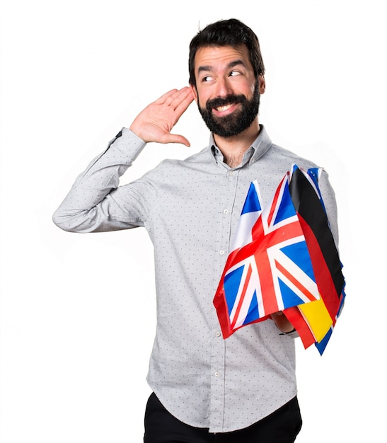 Handsome man with beard holding many flags and listening something