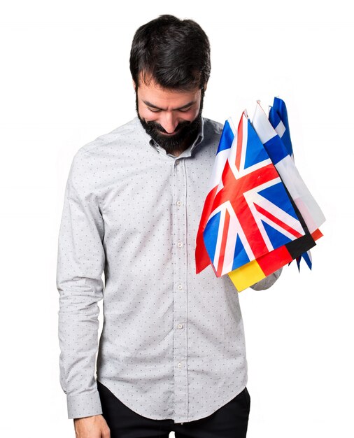 Handsome man with beard holding many flags and looking down