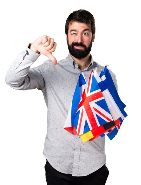 Handsome man with beard holding many flags and making bad signal