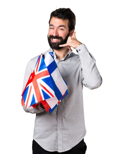 Uomo bello con la barba che tiene molte bandiere e che fa il telefono gesto