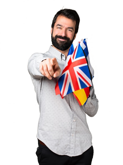 Free photo handsome man with beard holding many flags and pointing to the front