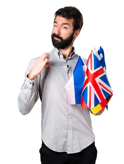 Handsome man with beard holding many flags proud of himself