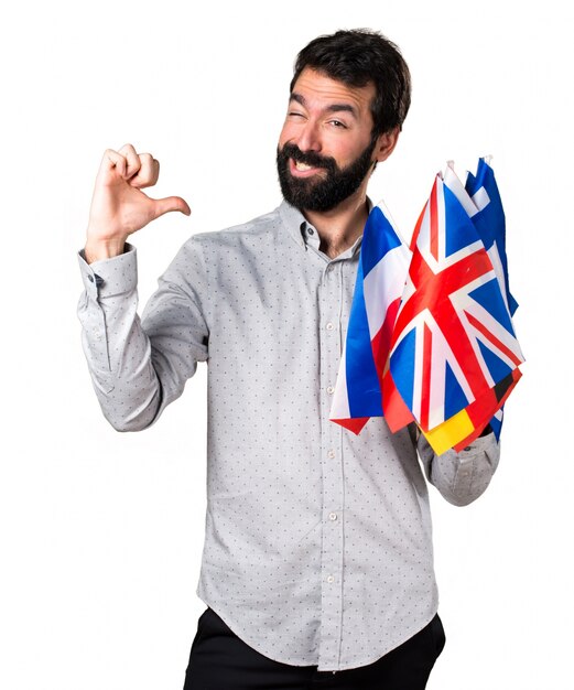 Handsome man with beard holding many flags proud of himself