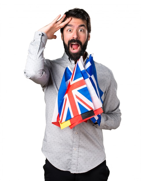 Handsome man with beard holding many flags and showing something