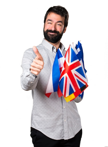 Handsome man with beard holding many flags and with thumb up