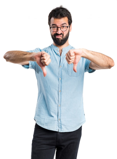 Handsome man with blue glasses doing bad signal