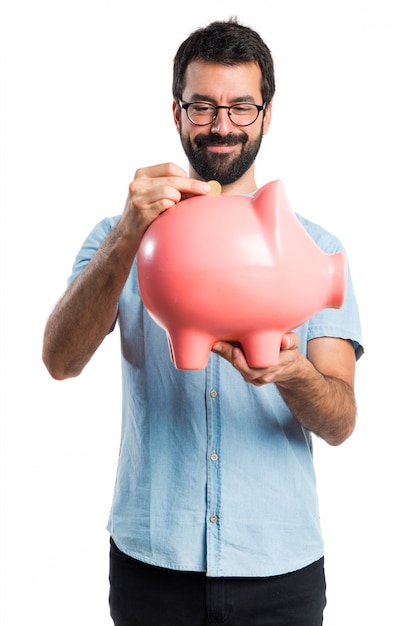Handsome man with blue glasses holding a piggybank