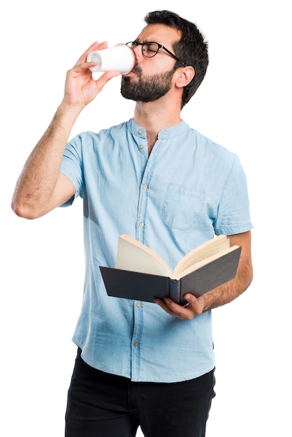 Free photo handsome man with blue glasses reading book and drinking coffee