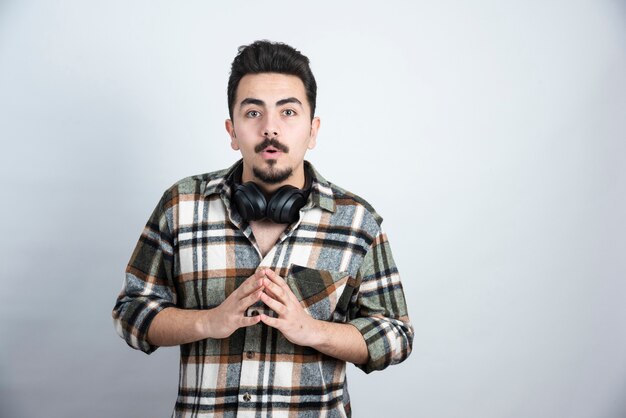 handsome man with headphones posing over white wall.