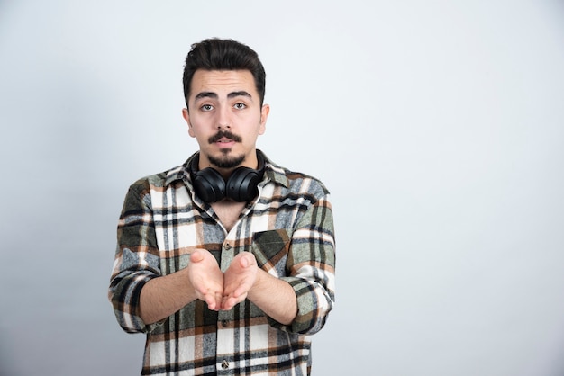 handsome man with headphones standing over white wall.