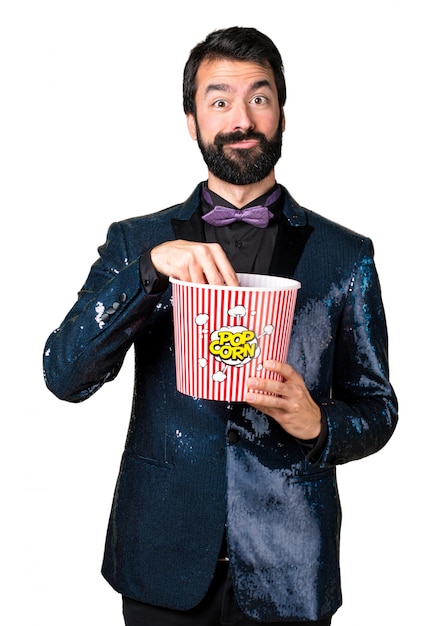 Uomo bello con giacca di sequin che mangia popcorn