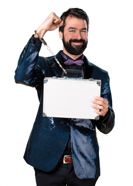 Handsome man with sequin jacket holding a briefcase with handcuffs