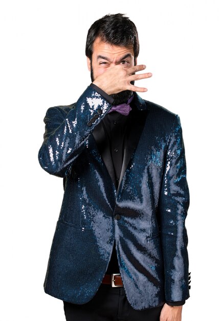 Handsome man with sequin jacket making smelling bad gesture