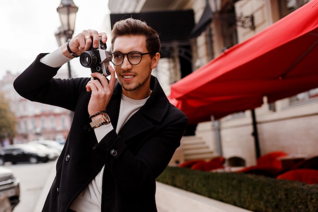 Handsome man with stylish hairstyle making photod in european city. Autumn season.