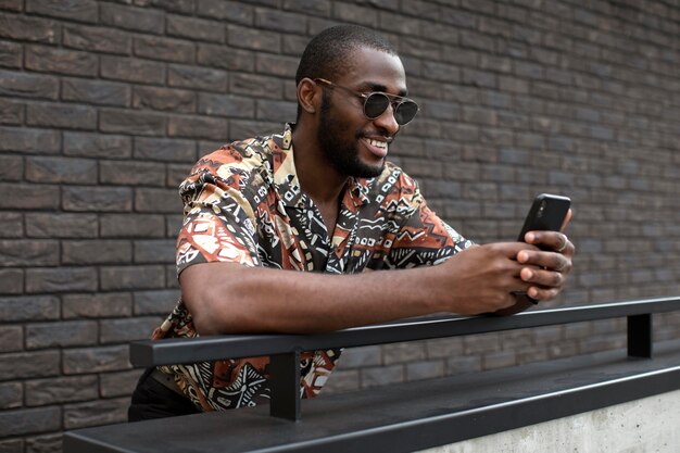 Handsome man with sunglasses using modern smartphone outdoors