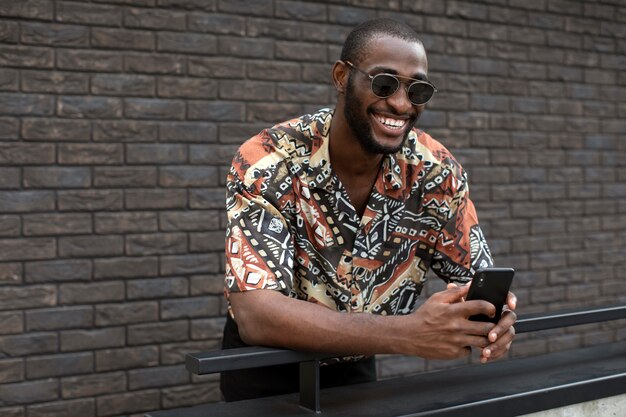 Free photo handsome man with sunglasses using modern smartphone outdoors