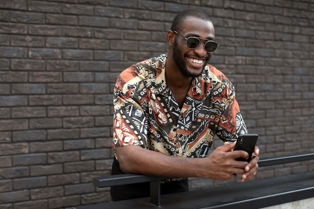 Handsome man with sunglasses using modern smartphone outdoors