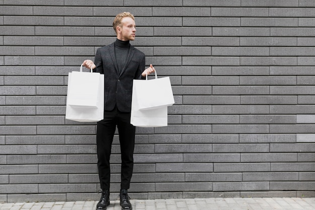 白い買い物袋を持つハンサムな男