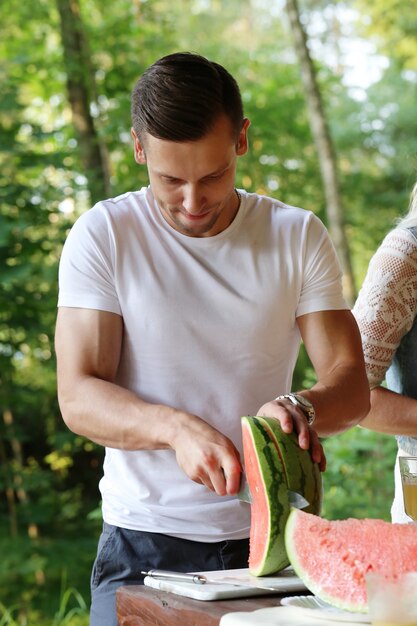 Handsome man with white t-shirt cutting watermelon