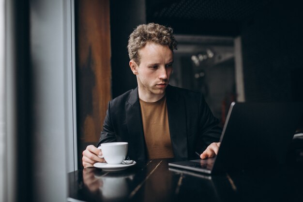 Handsome man working on a computer in a cafe and drinking coffee