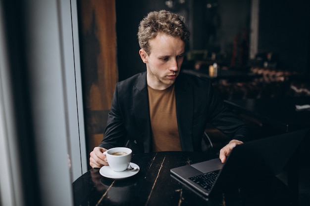 Handsome man working on a computer in a cafe and drinking coffee