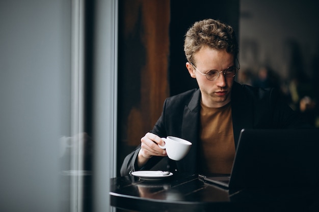 Handsome man working on a computer in a cafe and drinking coffee