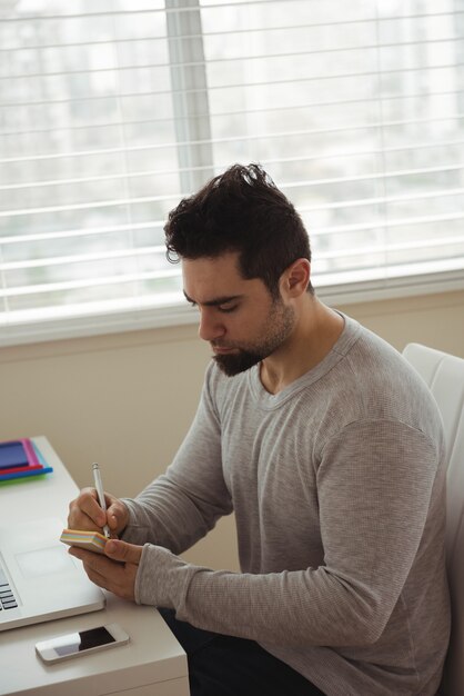 Handsome man writing on sticky note