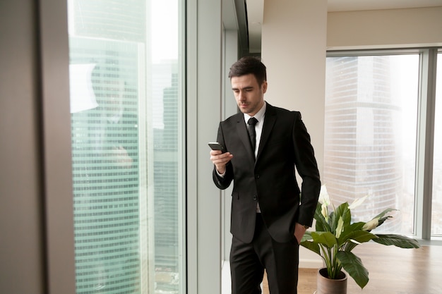 Handsome manager searching contact in smartphone