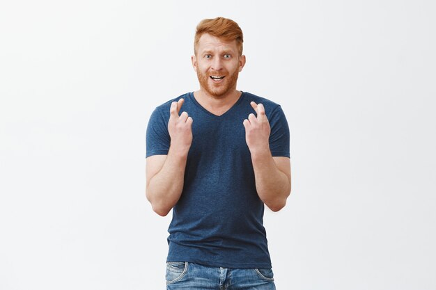 Handsome masculine redhead male model feeling nervous standing with fingers crossed