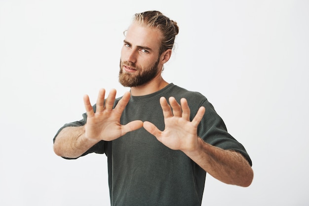 Foto gratuita bel ragazzo maturo con la barba, tenendosi per mano davanti a lui. ferma gesto