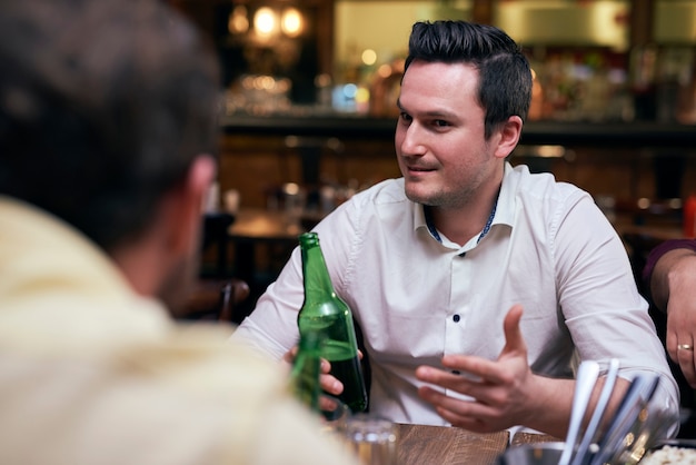 Free photo handsome men drinking beer in the pub