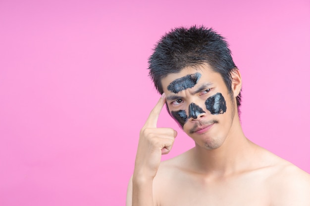 Handsome men who apply black cosmetics on their faces, showing various postures with a pink .