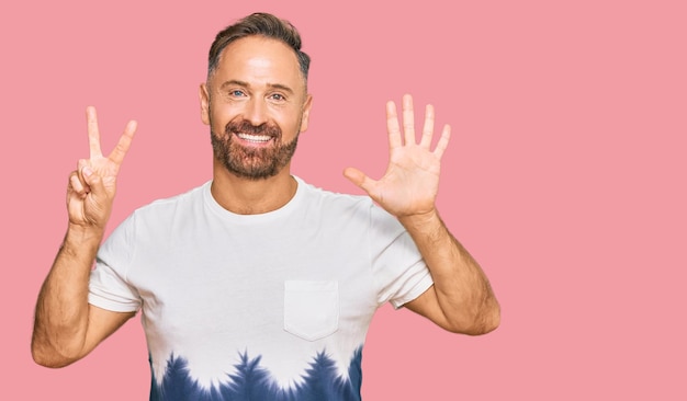 Free photo handsome middle age man wearing casual tie dye tshirt showing and pointing up with fingers number seven while smiling confident and happy